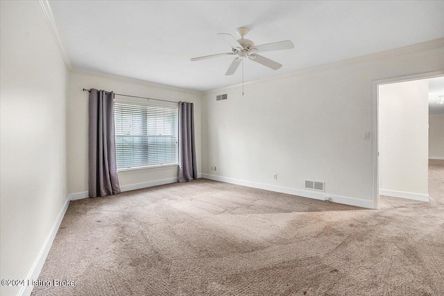 empty room with ceiling fan, light colored carpet, and ornamental molding