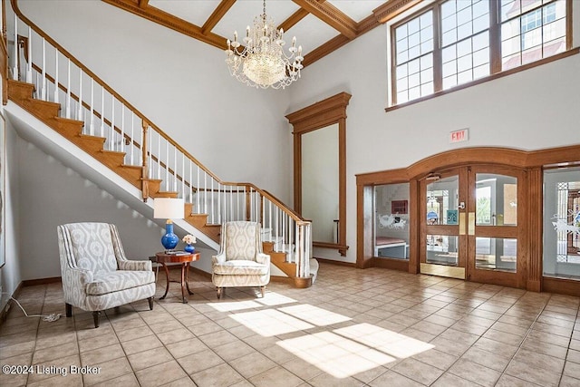 foyer entrance with light tile patterned floors, beam ceiling, coffered ceiling, a notable chandelier, and a towering ceiling