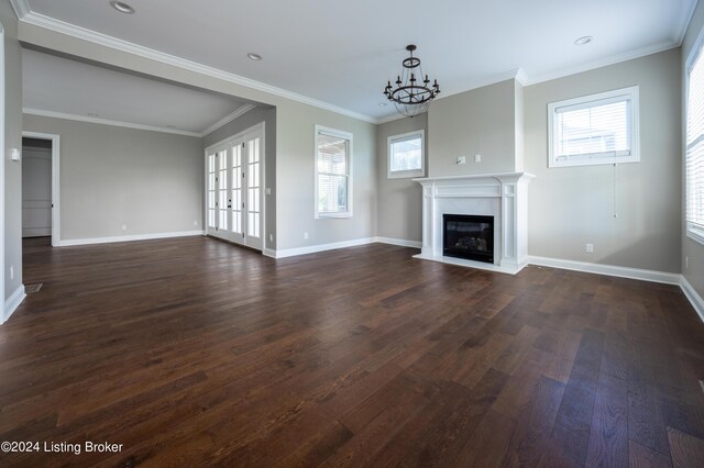 unfurnished living room with ornamental molding, dark hardwood / wood-style flooring, a chandelier, and plenty of natural light