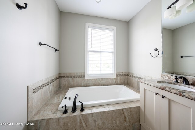 bathroom featuring tiled bath and vanity