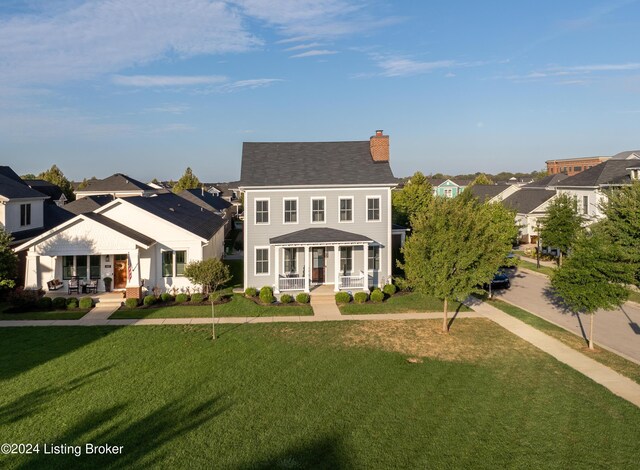 colonial inspired home featuring covered porch and a front yard