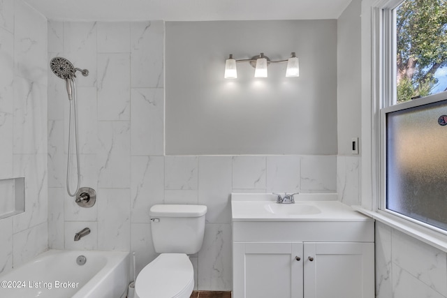 full bathroom with tile walls, tiled shower / bath combo, vanity, and toilet