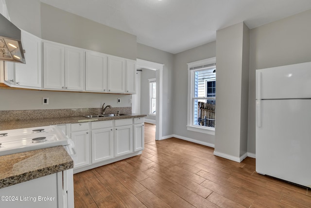 kitchen with light hardwood / wood-style floors, white cabinetry, light stone counters, white appliances, and sink