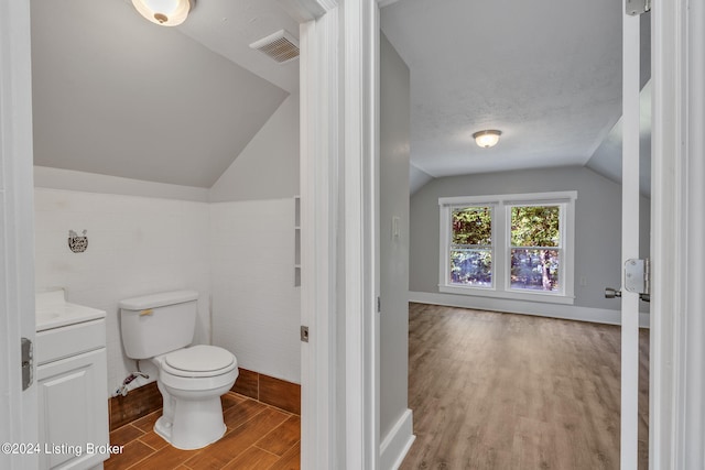 bathroom featuring vaulted ceiling, vanity, a textured ceiling, wood-type flooring, and toilet