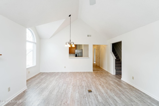 unfurnished living room with an inviting chandelier, light wood-type flooring, and high vaulted ceiling