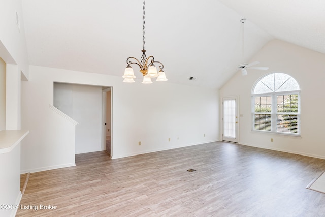 empty room with light wood-type flooring, ceiling fan with notable chandelier, and high vaulted ceiling