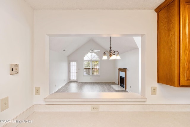 unfurnished room featuring ceiling fan with notable chandelier, lofted ceiling, and light hardwood / wood-style flooring