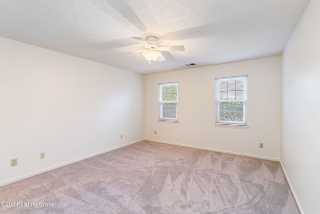 spare room with a textured ceiling, light carpet, and ceiling fan