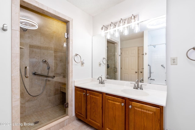 bathroom featuring vanity, a textured ceiling, and a shower with door