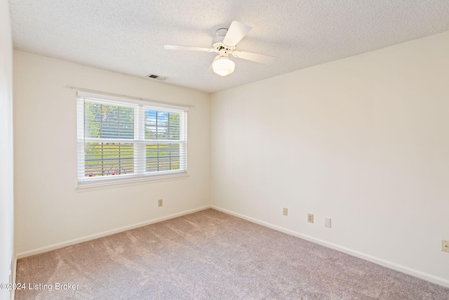 empty room with ceiling fan, a textured ceiling, and carpet