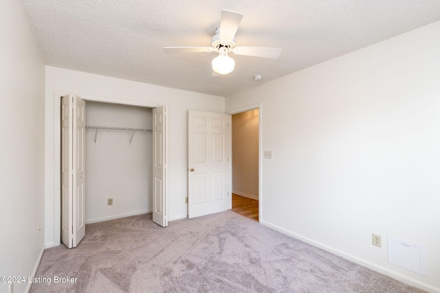 unfurnished bedroom with ceiling fan, a textured ceiling, a closet, and light carpet