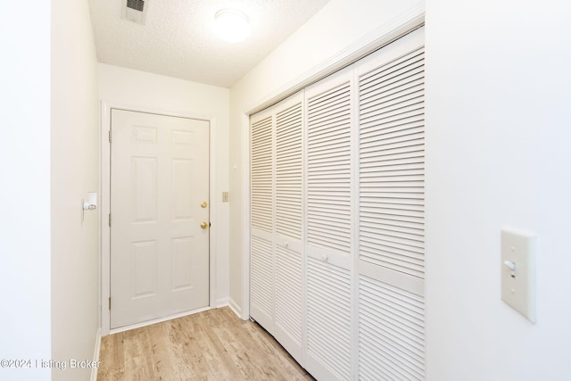 corridor featuring a textured ceiling and light hardwood / wood-style flooring