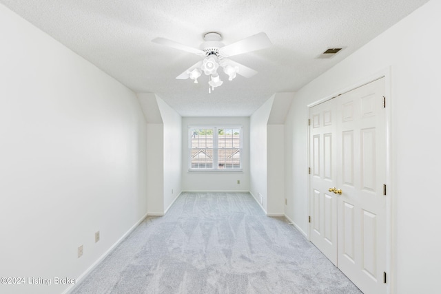 empty room featuring ceiling fan, a textured ceiling, and light carpet