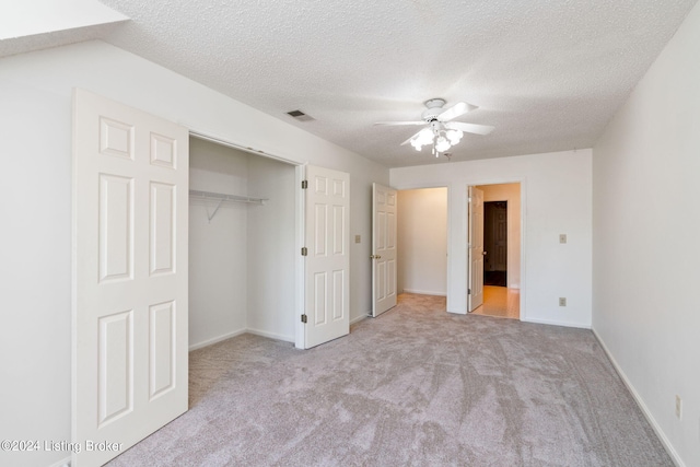 unfurnished bedroom featuring a closet, ceiling fan, light colored carpet, and a textured ceiling