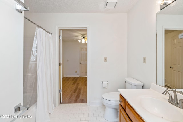 full bathroom with a textured ceiling, vanity, toilet, and ceiling fan