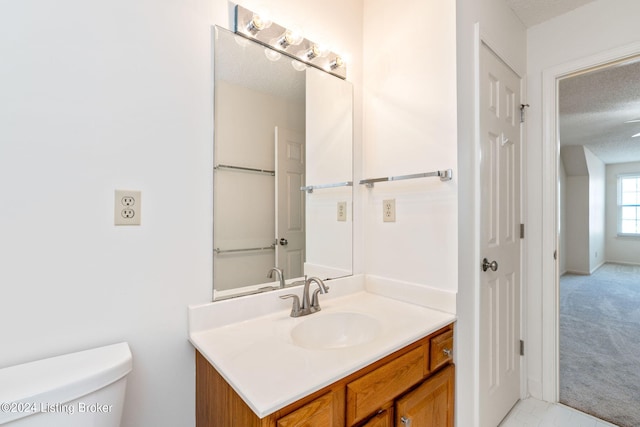 bathroom featuring a textured ceiling, vanity, and toilet