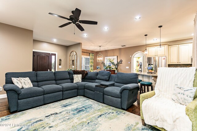 living room with ceiling fan with notable chandelier and dark hardwood / wood-style floors