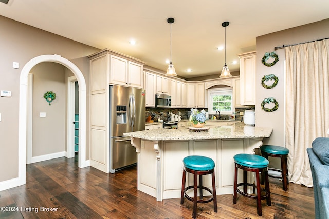 kitchen featuring pendant lighting, kitchen peninsula, appliances with stainless steel finishes, dark hardwood / wood-style flooring, and light stone countertops