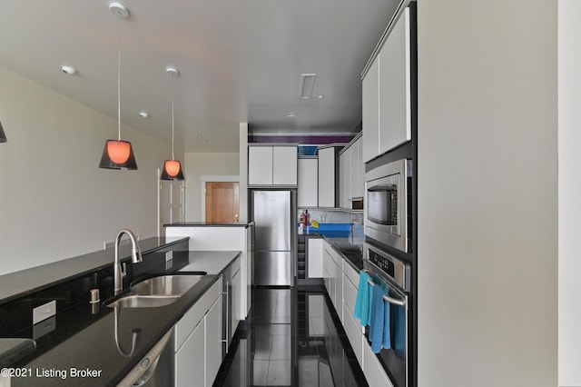 kitchen featuring white cabinetry, a sink, dark countertops, and appliances with stainless steel finishes
