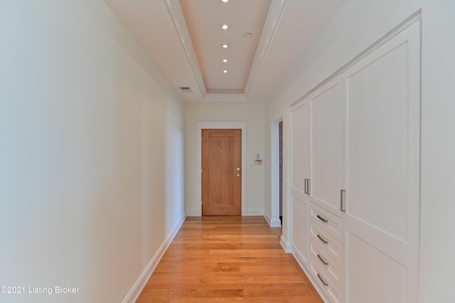 hall with light hardwood / wood-style flooring and a tray ceiling