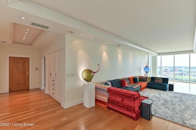 living room featuring a wall of windows, a raised ceiling, and hardwood / wood-style floors