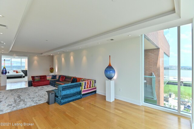 living room featuring a water view, a tray ceiling, and hardwood / wood-style floors