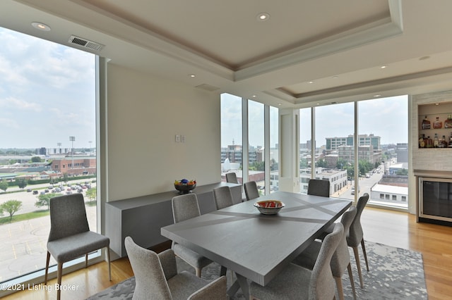 dining space featuring expansive windows, a tray ceiling, light wood-type flooring, and a wealth of natural light