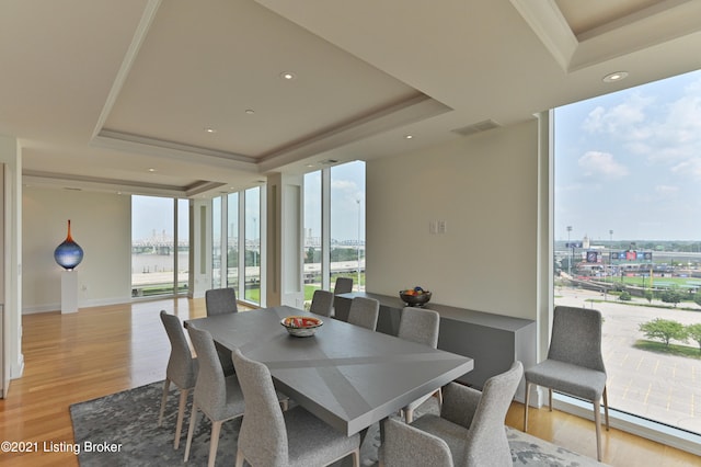 dining room featuring light wood-type flooring and a raised ceiling