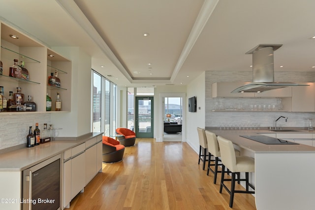 kitchen with backsplash, white cabinetry, and beverage cooler