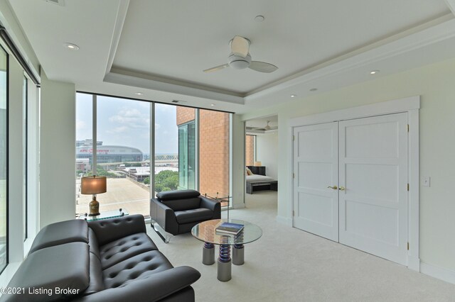 living room featuring carpet, a tray ceiling, and ceiling fan