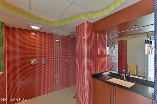 interior space featuring walk in shower, vanity, and a drop ceiling