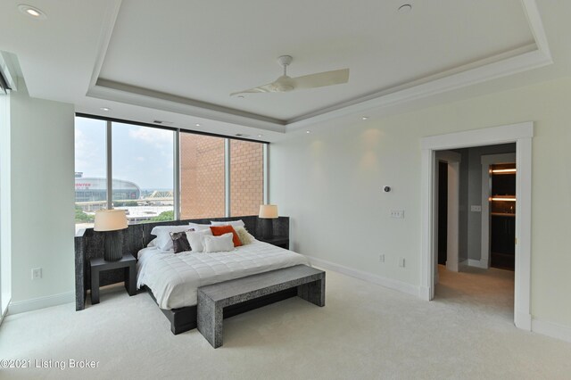 bedroom with a raised ceiling, ceiling fan, and light colored carpet