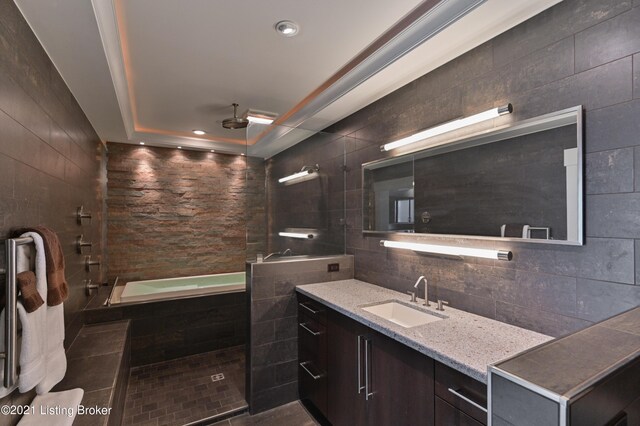 bathroom featuring tile walls, a raised ceiling, vanity, and separate shower and tub