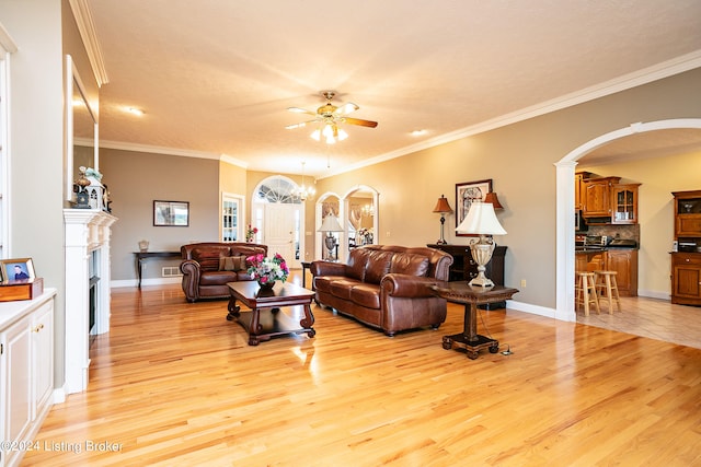 living room with ceiling fan with notable chandelier, light hardwood / wood-style floors, and ornamental molding