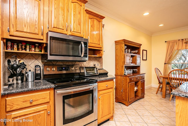 kitchen with light tile patterned flooring, decorative backsplash, appliances with stainless steel finishes, ornamental molding, and dark stone countertops