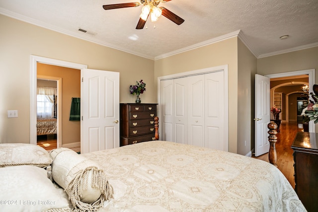 bedroom featuring a closet, ceiling fan, a textured ceiling, and crown molding