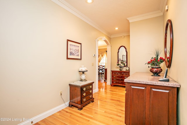 hallway with light wood-type flooring and crown molding