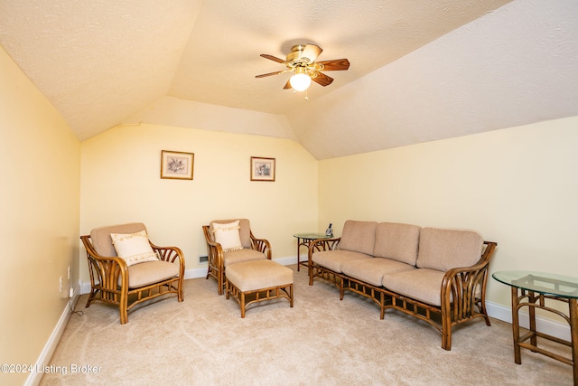 interior space with a textured ceiling, lofted ceiling, ceiling fan, and light colored carpet