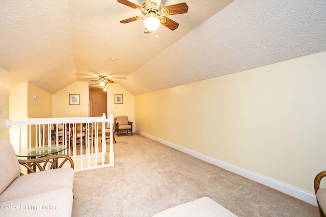 interior space with a textured ceiling, carpet, lofted ceiling, and ceiling fan