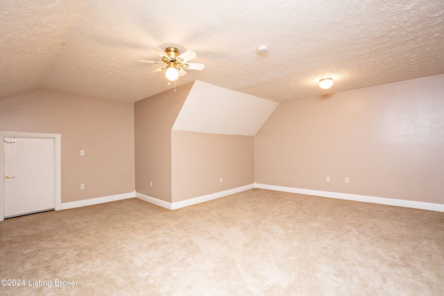 additional living space featuring ceiling fan, a textured ceiling, light carpet, and vaulted ceiling