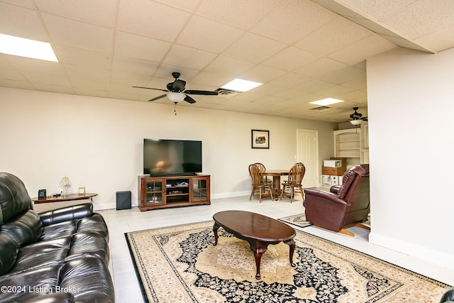 tiled living room with a drop ceiling and ceiling fan