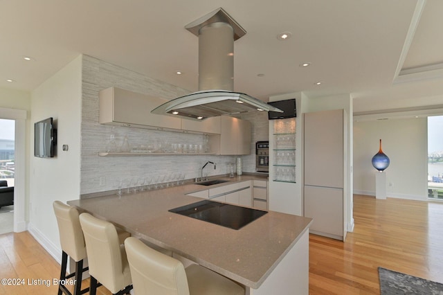 222 E Witherspoon St Unit 703-704, Louisville, KY 40202 - kitchen featuring a sink, open shelves, tasteful backsplash, black electric stovetop, and island range hood
