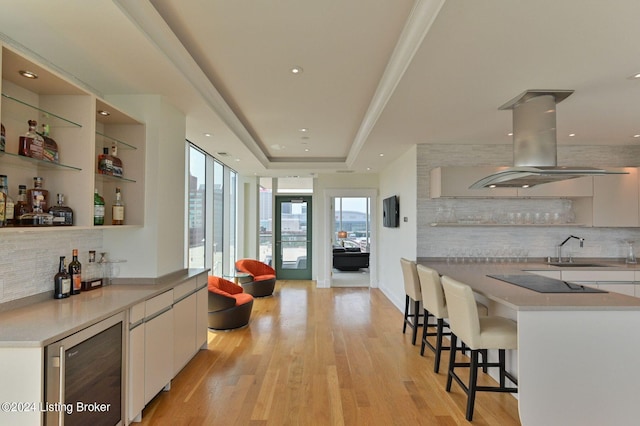 kitchen with wine cooler, light wood-type flooring, tasteful backsplash, and white cabinetry