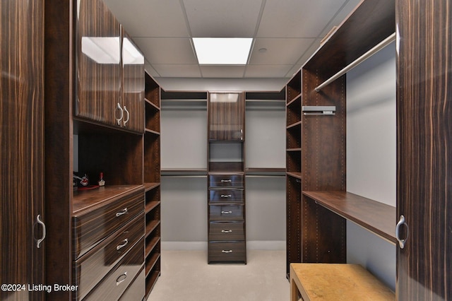 walk in closet with light colored carpet and a drop ceiling