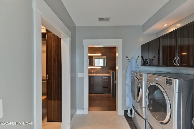 washroom with separate washer and dryer, light tile patterned flooring, and cabinets