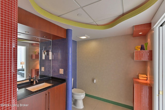 bathroom with a paneled ceiling, vanity, toilet, and tile patterned floors