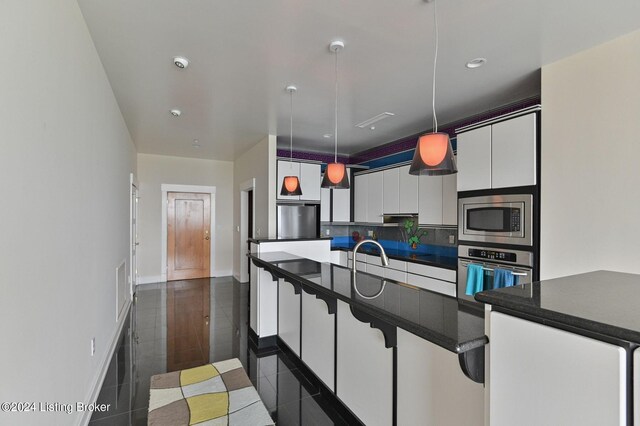 kitchen with tasteful backsplash, a breakfast bar area, white cabinetry, hanging light fixtures, and stainless steel appliances