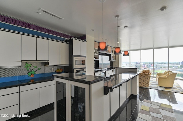 kitchen featuring appliances with stainless steel finishes, decorative light fixtures, a healthy amount of sunlight, and white cabinetry