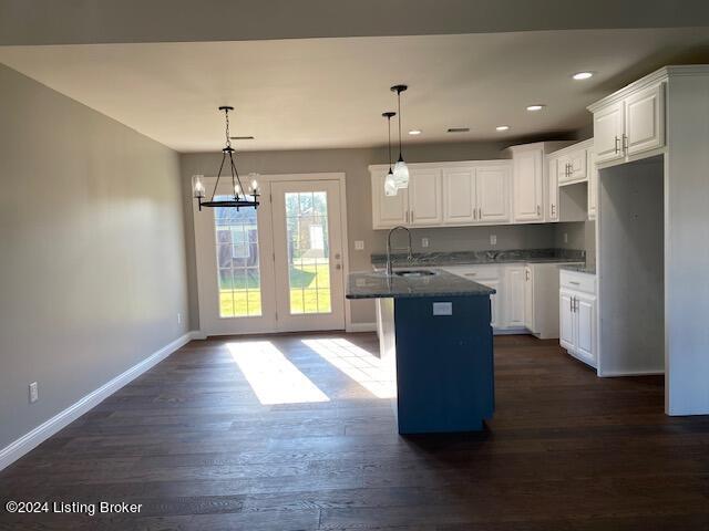 kitchen with white cabinets, a center island, hanging light fixtures, and dark hardwood / wood-style flooring