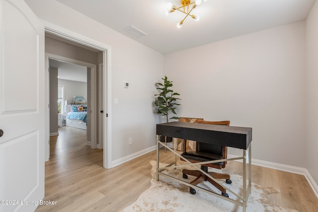 home office with light hardwood / wood-style flooring and a notable chandelier